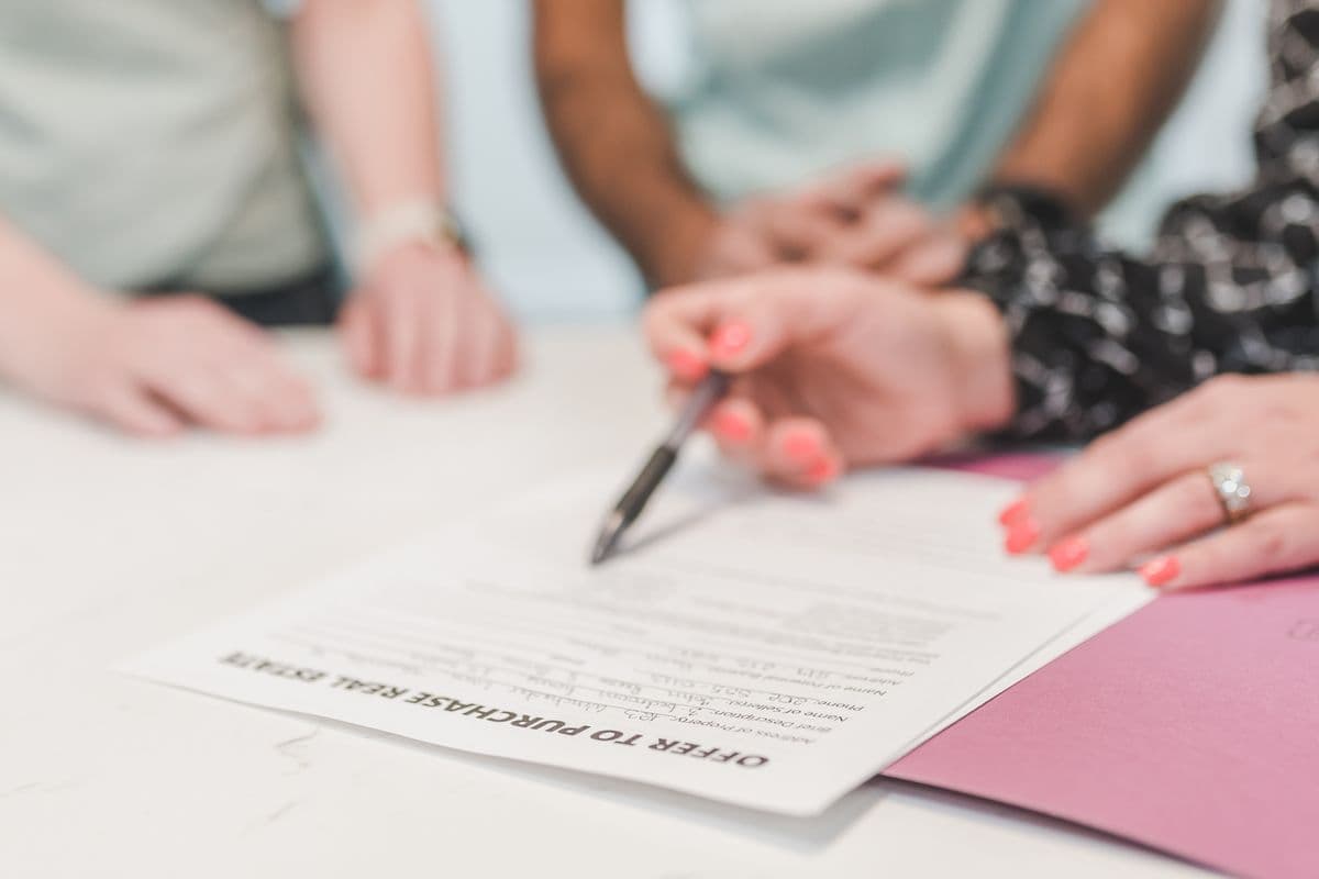 Three people signing an Offer to Purchase Real Estate at a table